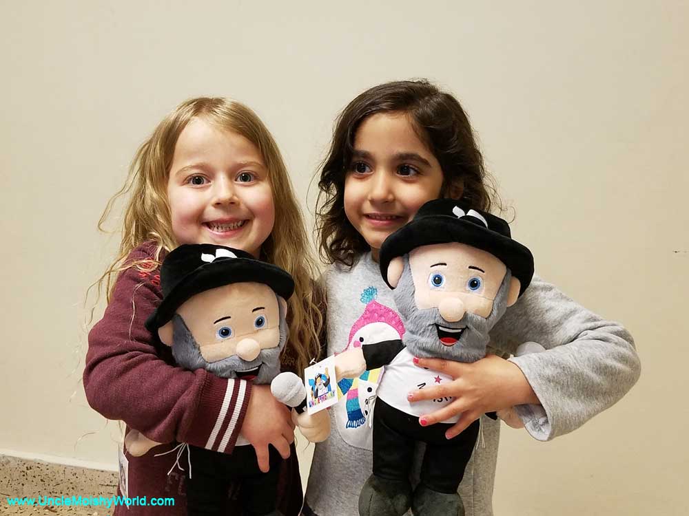 Two beautiful girls pose with their new Uncle Moishy plush toys.